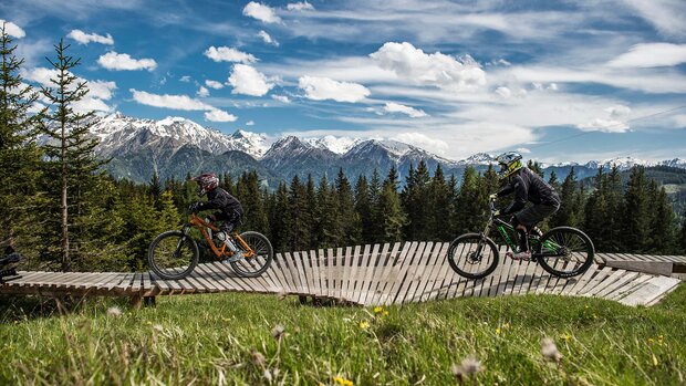 Mountainbiker auf einem Weg mit Bergsee im Hintergrund