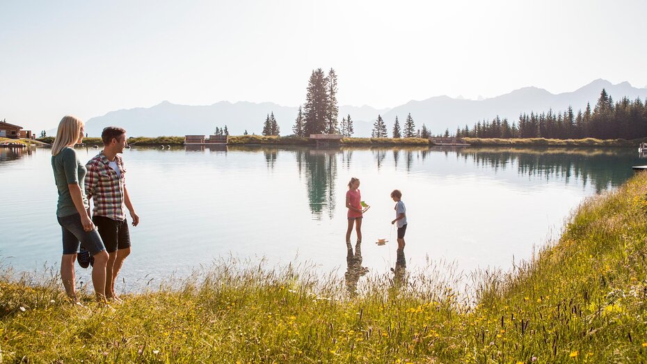 Person am Bergsee mit Blick auf die Berge
